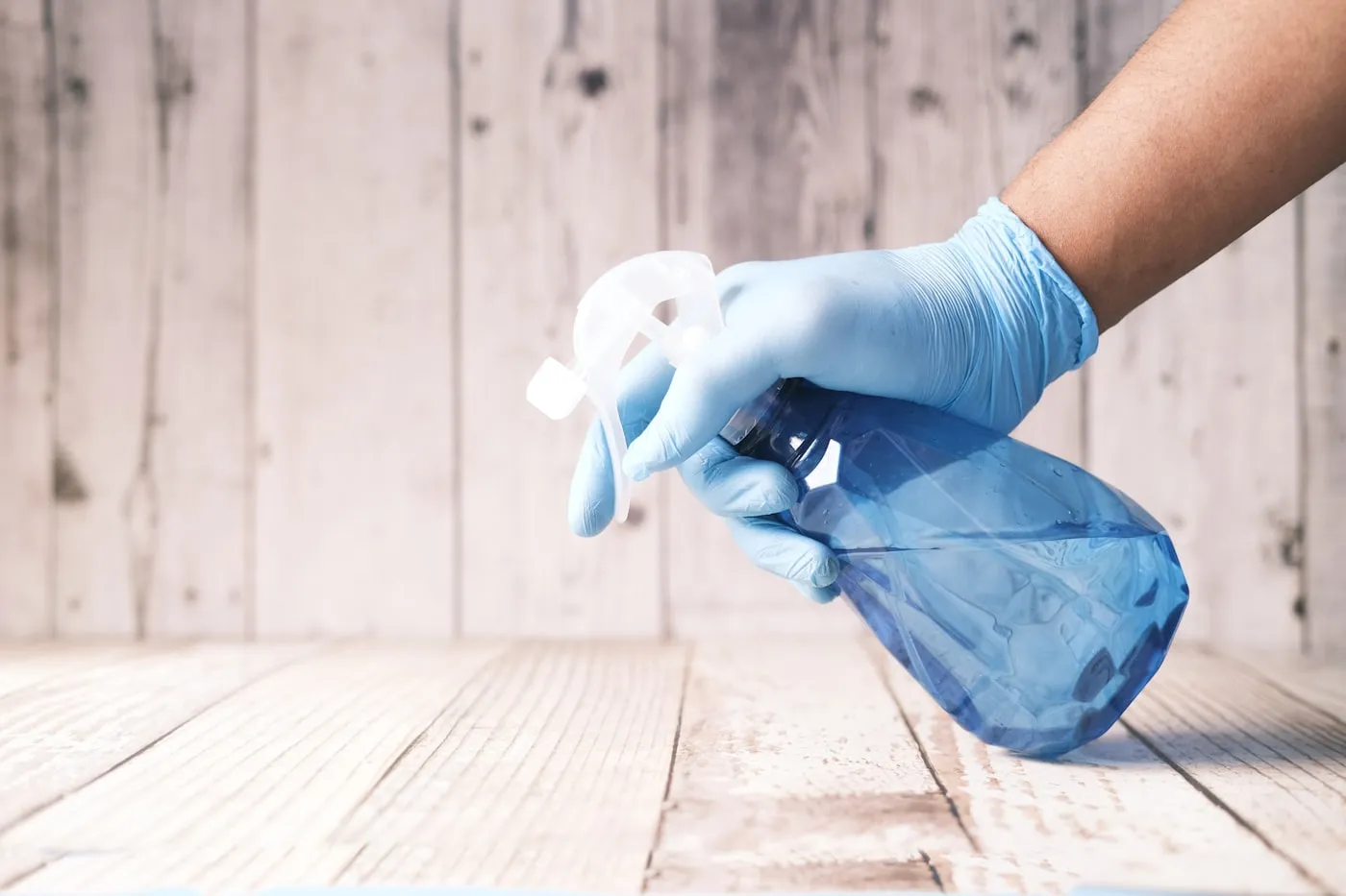 Gloved cleaner spraying cleaning solution onto a surface during a deep clean