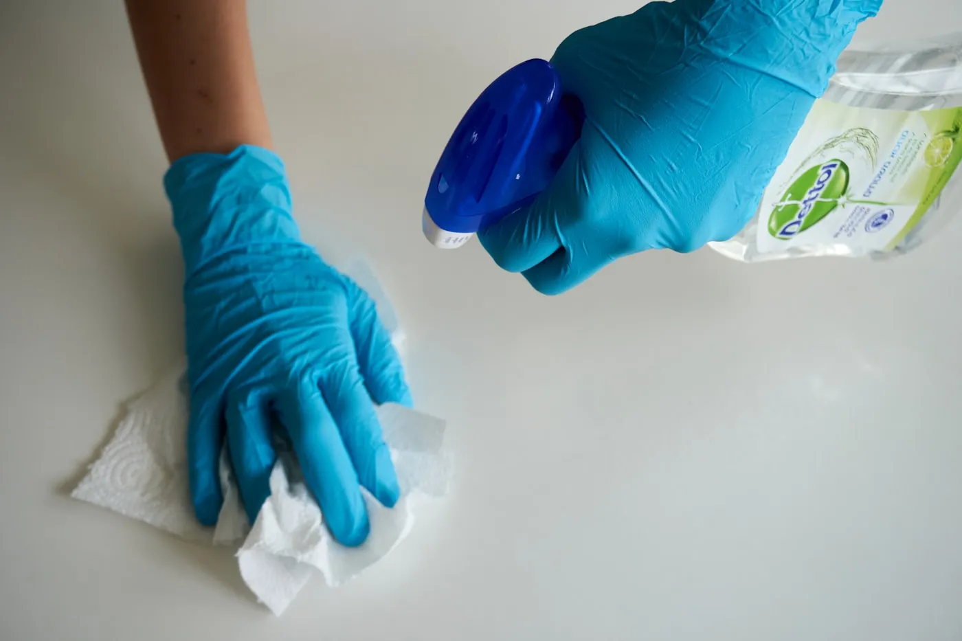 Gloved hands wiping down a kitchen counter during a routine clean